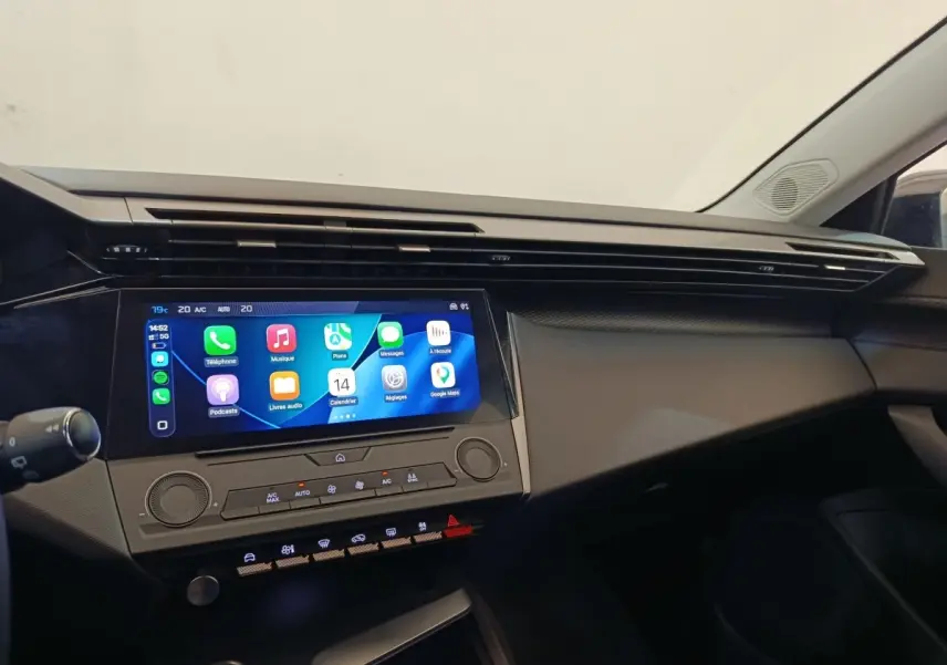 Tableau de bord intérieur de Peugeot 308 2023, vue de face, écran tactile central allumé avec interface Apple CarPlay.