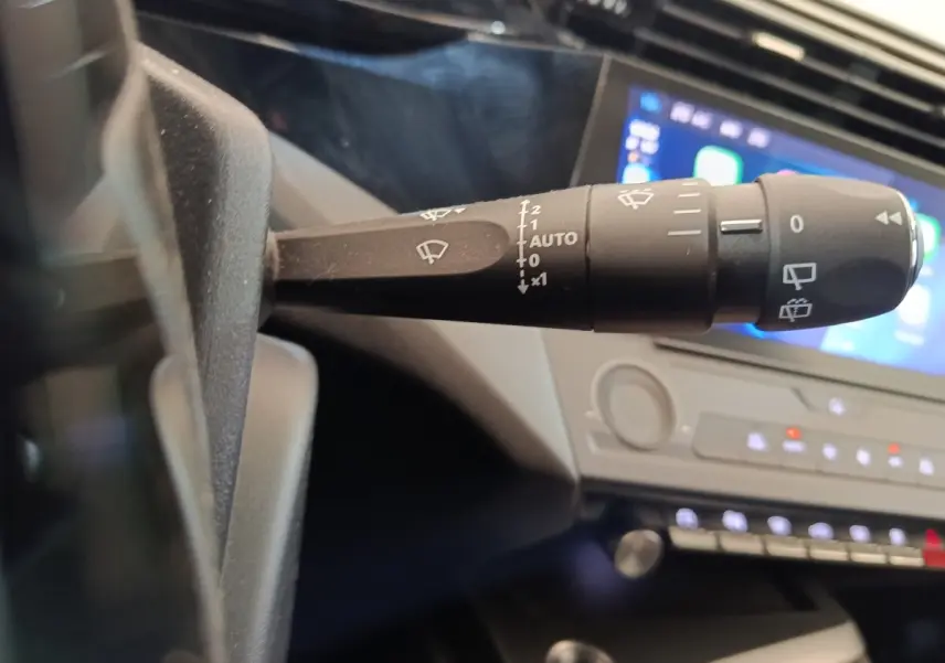 Gros plan sur la commande d’essuie-glace à gauche du volant dans l’habitacle sombre de la Peugeot 308 2023.