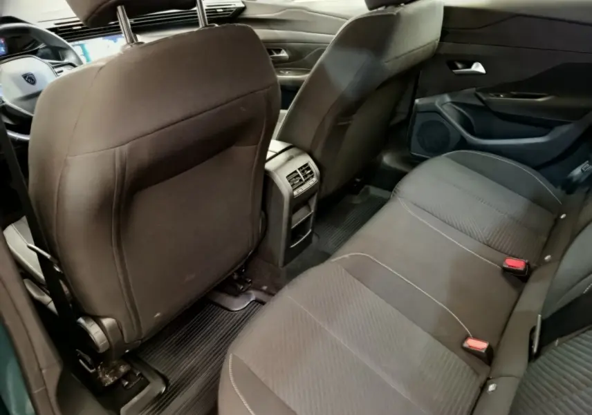 Vue intérieure arrière droite du Peugeot 308 2023 avec sièges tissu noirs et console centrale avec aérateurs.