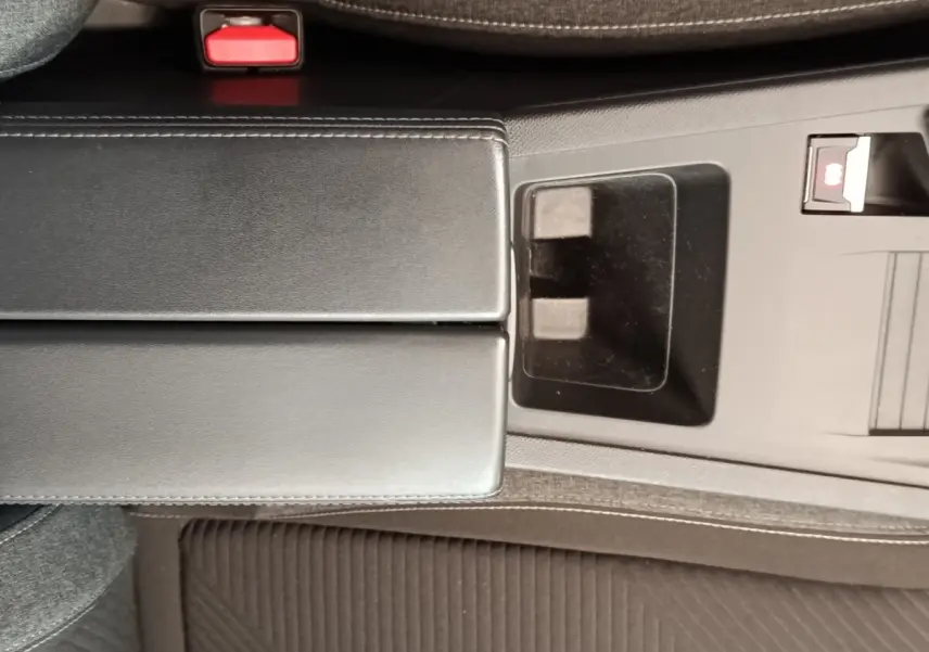 Vue rapprochée de la console centrale noire de la Peugeot 308 2023 avec accoudoir et frein à main électrique.
