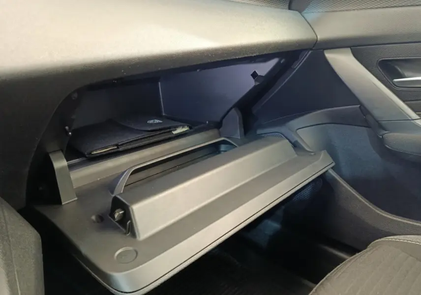 Vue intérieure côté passager de la Peugeot 308 2023 essence, boîte auto, avec boîte à gants ouverte et rangement noir.