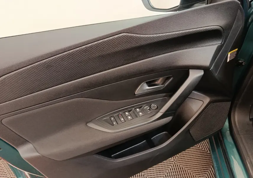 Vue rapprochée de la porte avant gauche noire de la Peugeot 308 2023, avec commandes de vitres et haut-parleur intégré.