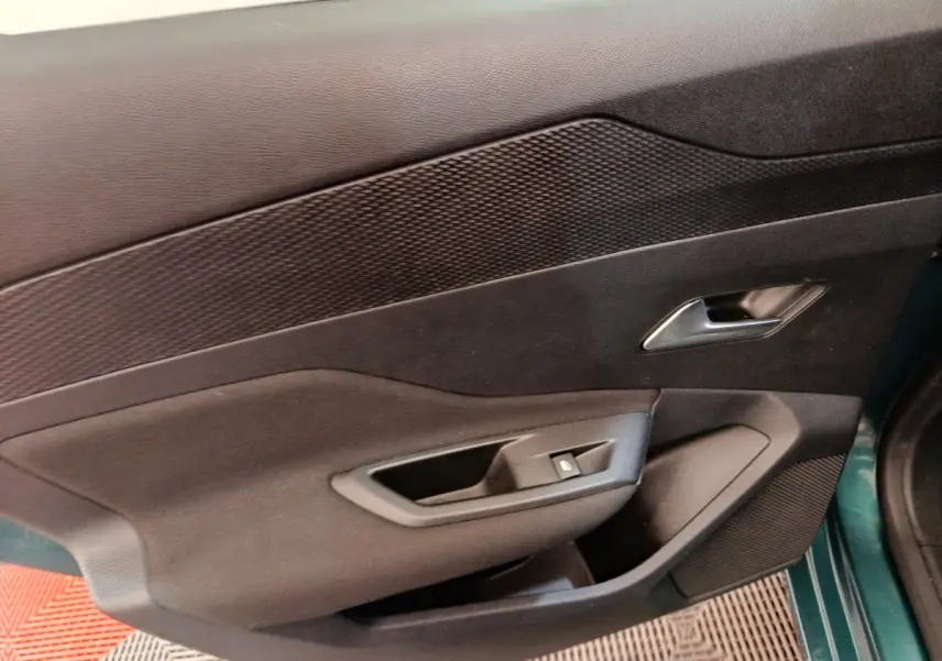 Vue intérieure sur la porte avant gauche noire avec poignée argentée et commande de fenêtre d’une Peugeot 308 2023.