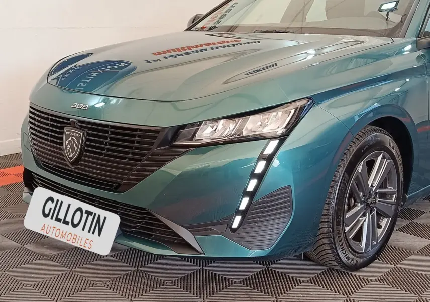 Vue 3/4 avant droit d'une Peugeot 308 2023 vert métallisé avec signature lumineuse LED verticale et calandre noire.