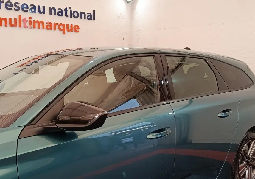 Vue latérale gauche d'une Peugeot 308 2023 vert métallisé avec rétroviseur noir et poignées de porte intégrées.