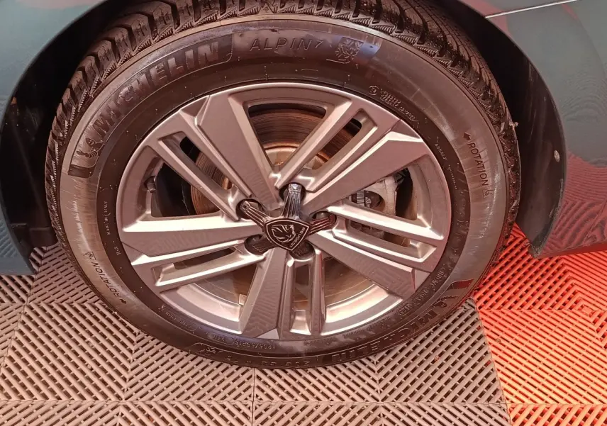 Gros plan sur la roue avant droite d'une Peugeot 308 2023, jante alliage grise et pneu Michelin Alpine.