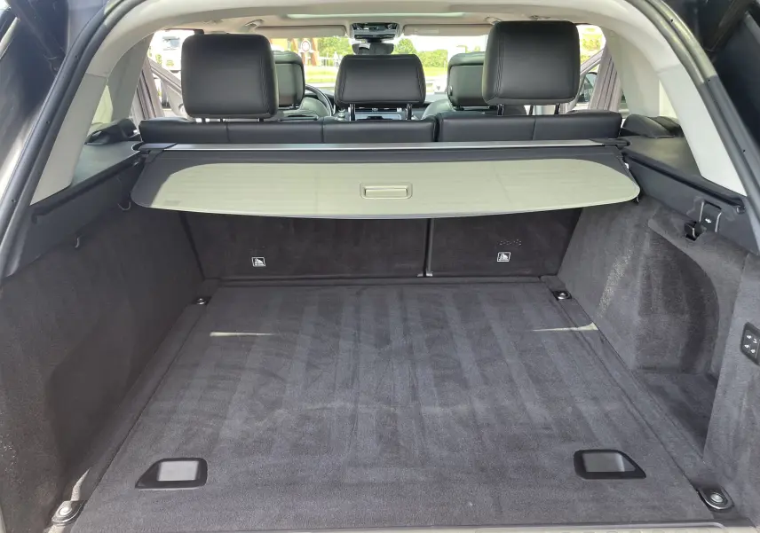 Coffre spacieux du Range Rover Sport D300 gris Eiger, vue arrière ouverte avec cache-bagages et sièges noirs visibles.