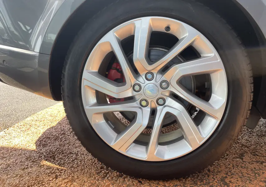Gros plan sur la jante alu 21 pouces argentée et le frein rouge du Range Rover Sport gris Eiger côté arrière.