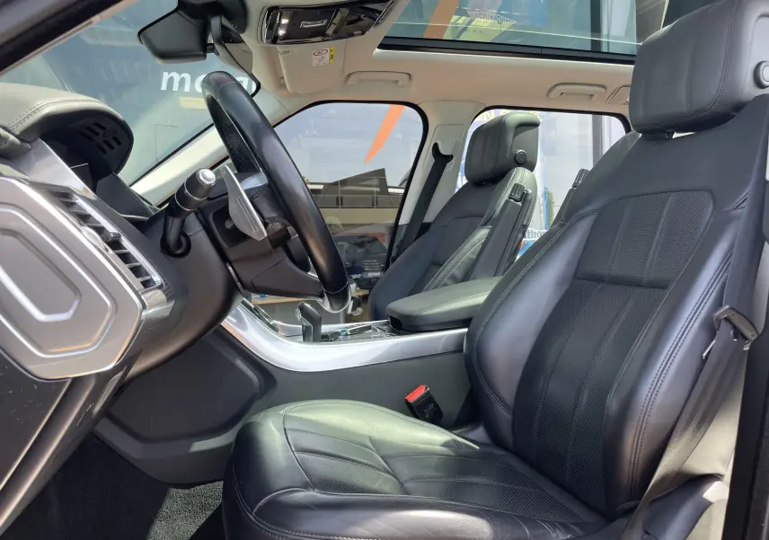 Vue intérieure côté conducteur du Range Rover Sport 2021 avec sellerie cuir noir et toit panoramique lumineux.