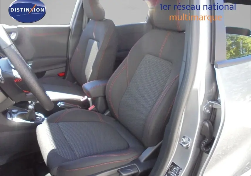 Vue intérieure côté conducteur du Ford Puma gris Solar Metal, sièges tissu noir avec surpiqûres rouges et boîte manuelle visible.