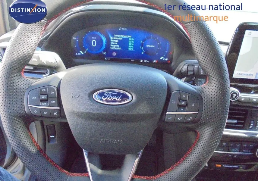 Vue rapprochée du volant perforé avec surpiqûres rouges et tableau de bord numérique de la Ford Puma gris Solar Metal.