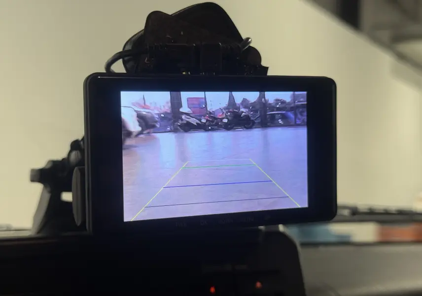 Écran de caméra de recul dans un Suzuki Jimny bleu 2021, vue intérieure avec guidage de trajectoire visible.