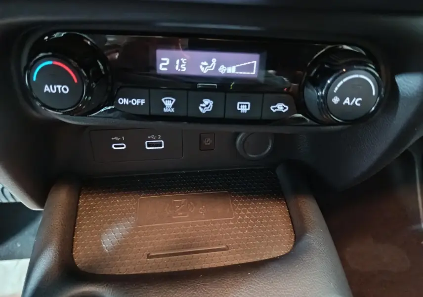 Détail de la console centrale du Nissan Juke 2025, montrant les commandes de climatisation et la zone de recharge sans fil.