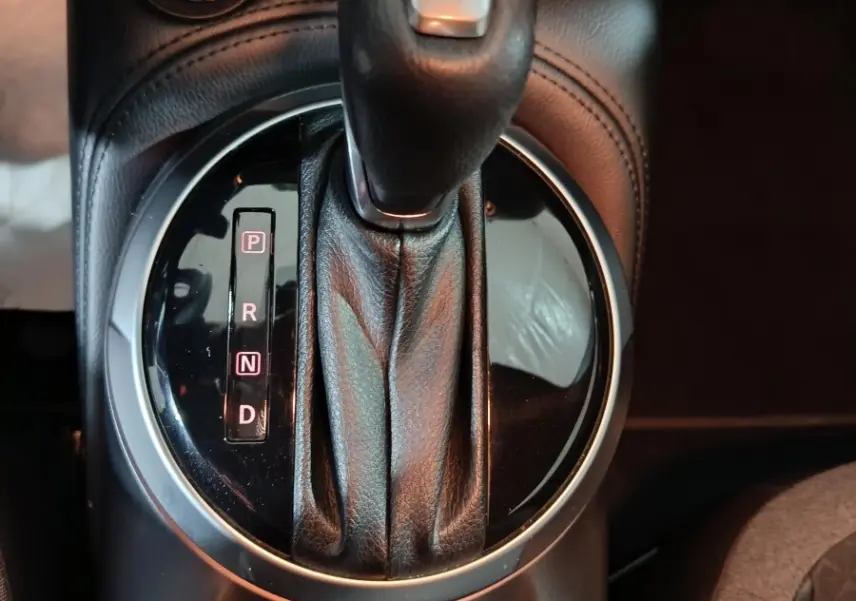 Gros plan sur la console centrale du Nissan Juke gris foncé 2025, avec levier de vitesse automatique et bouton démarrage.