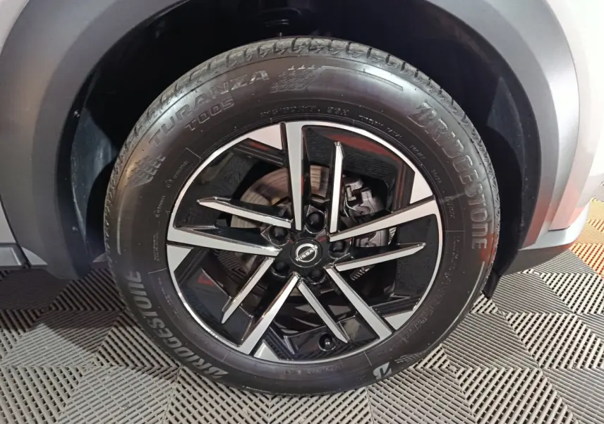 Gros plan sur la roue avant droite du Nissan Juke gris foncé, jante alliage noir et argent avec pneu Bridgestone.