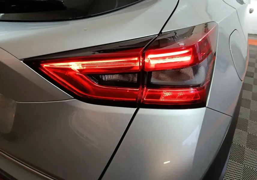 Gros plan sur le feu arrière droit rouge vif d’un Nissan Juke gris foncé 2025, soulignant ses lignes modernes.