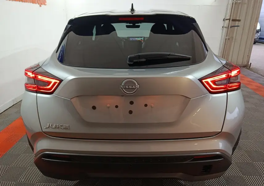 Vue arrière d'un Nissan Juke gris foncé 2025 avec feux LED allumés dans un garage fermé.