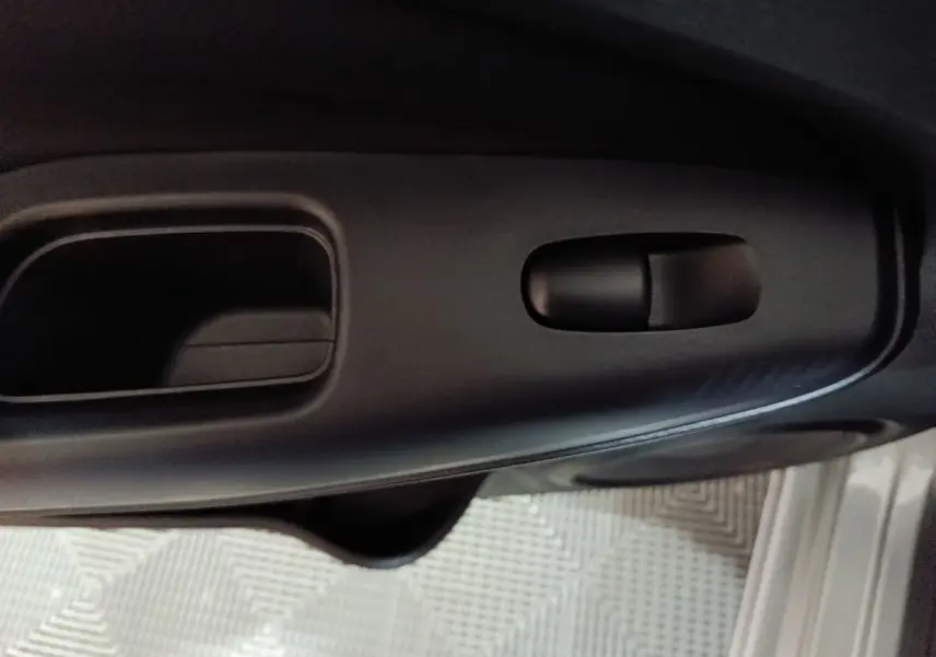 Gros plan sur la poignée intérieure noire de la porte côté conducteur du Nissan Juke gris foncé 2025.