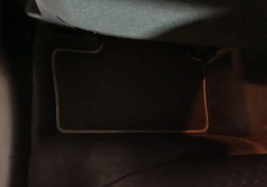 Gros plan sur le tapis de sol noir à bordures claires dans l'habitacle du Nissan Juke gris foncé 2025.