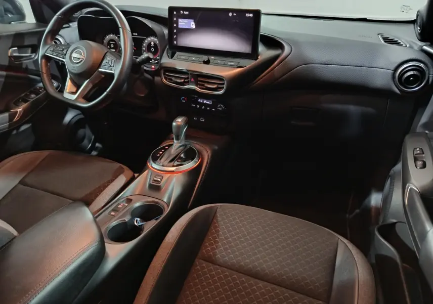 Vue intérieure côté conducteur du Nissan Juke 2025 gris foncé, avec tableau de bord numérique et écran tactile central.