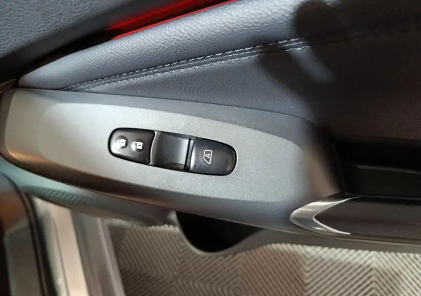 Détail des commandes de verrouillage centralisé sur la portière côté conducteur du Nissan Juke gris foncé 2025.