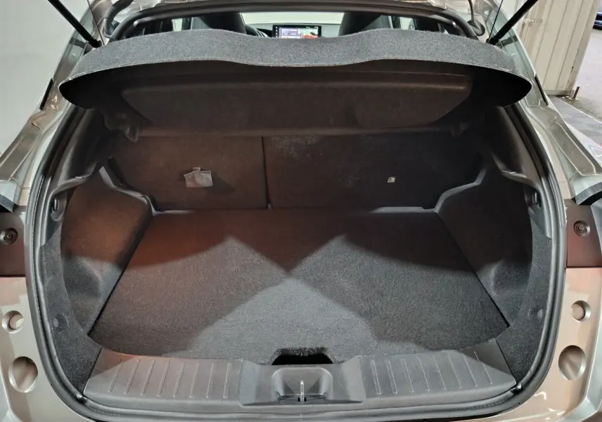 Coffre ouvert vu de l'arrière d'un Nissan Juke gris foncé, montrant l'espace de chargement vide et la tablette arrière.