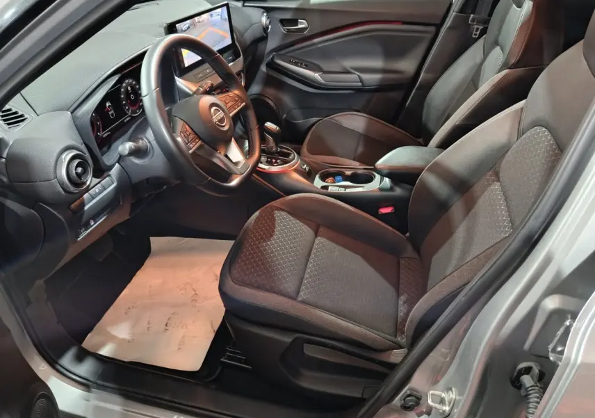 Intérieur avant droit du Nissan Juke gris foncé 2025, avec tableau de bord numérique et écran tactile central.