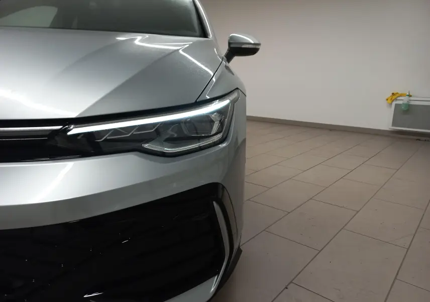 Gros plan sur l'avant droit de la Volkswagen Golf 1.5 eTSI R-Line argent dolomite avec phare LED allumé.