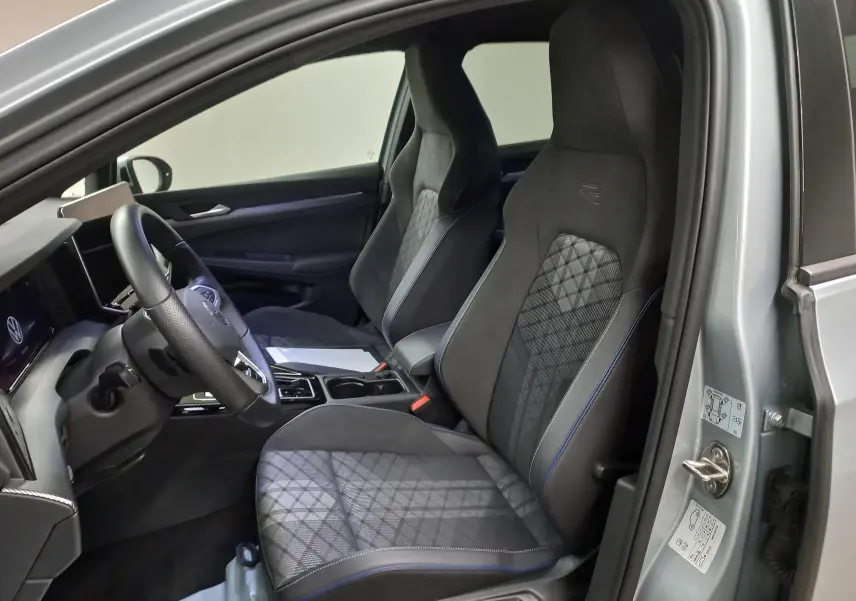 Intérieur avant droit de la Volkswagen Golf 1.5 eTSI R-Line argent Dolomite avec sièges sport et détails bleus.