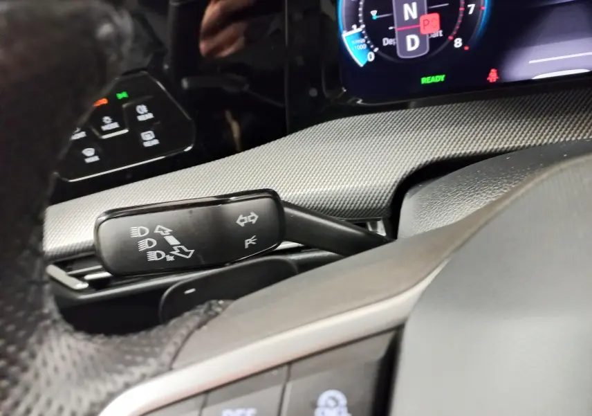 Détail du commodo de clignotants et tableau de bord numérique dans l'habitacle d'une Volkswagen Golf 1.5 eTSI R-Line 2025.