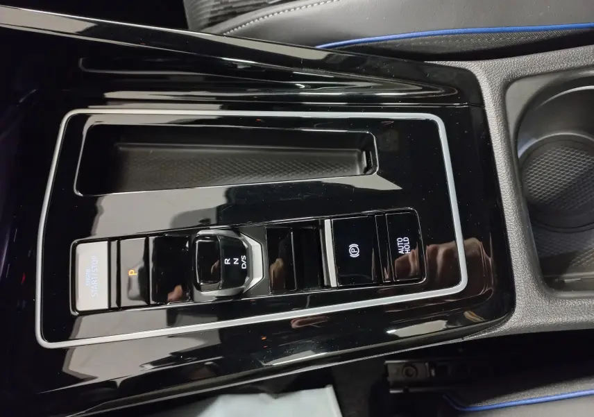 Vue rapprochée de la console centrale noire brillante de la Volkswagen Golf 1.5 eTSI 150 DSG7 R-Line Edition avec commandes de boîte auto.