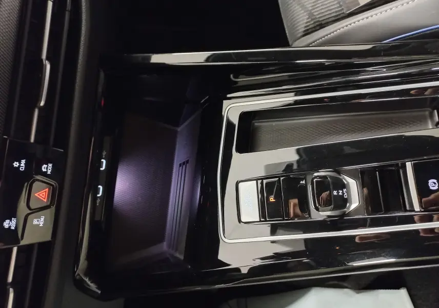 Vue rapprochée de la console centrale noire brillante de la Volkswagen Golf 1.5 eTSI R-Line avec sélecteur de boîte auto et bouton start/stop.