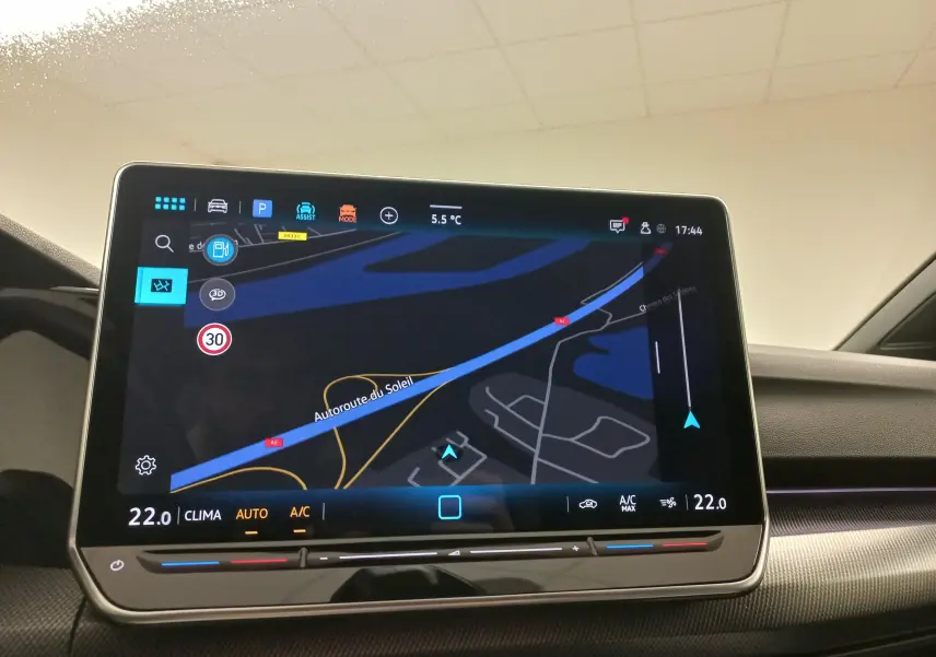 Écran tactile central affichant la navigation et la climatisation dans une Volkswagen Golf 2025, intérieur moderne.