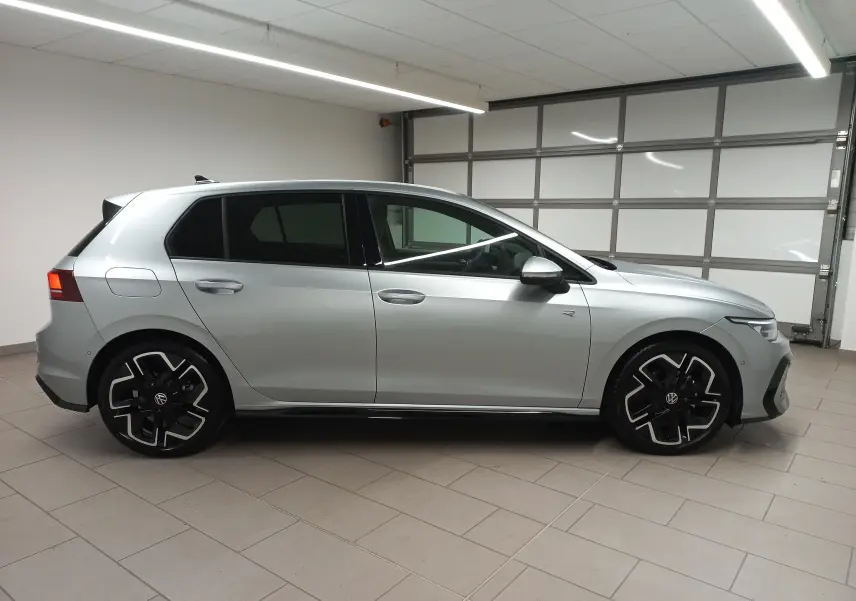 Profil droit d'une Volkswagen Golf 1.5 eTSI R-Line Edition 2025 en argent dolomite, avec jantes noires et détails sportifs.