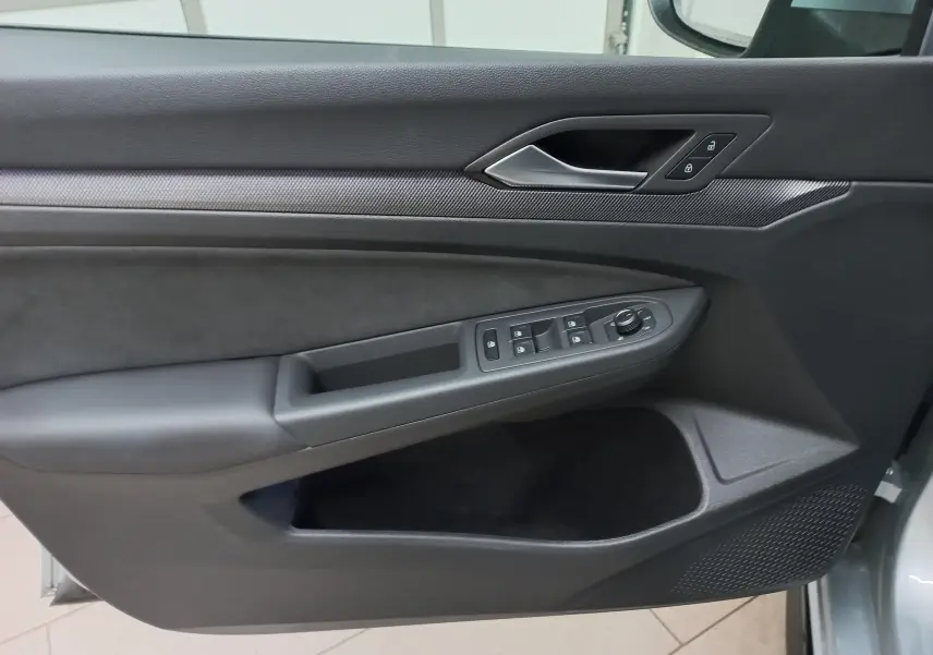 Vue rapprochée de la porte avant gauche de la Volkswagen Golf 1.5 eTSI 150 DSG7 R-Line argent dolomite avec commandes électriques.