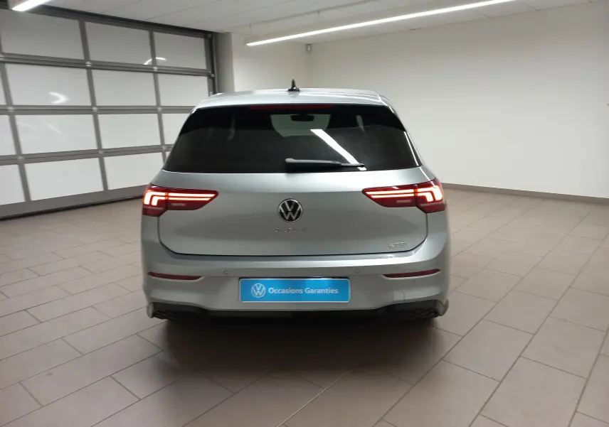 Vue arrière d'une Volkswagen Golf 1.5 eTSI 150 DSG7 R-Line Edition en argent dolomite avec feux LED allumés dans un garage.