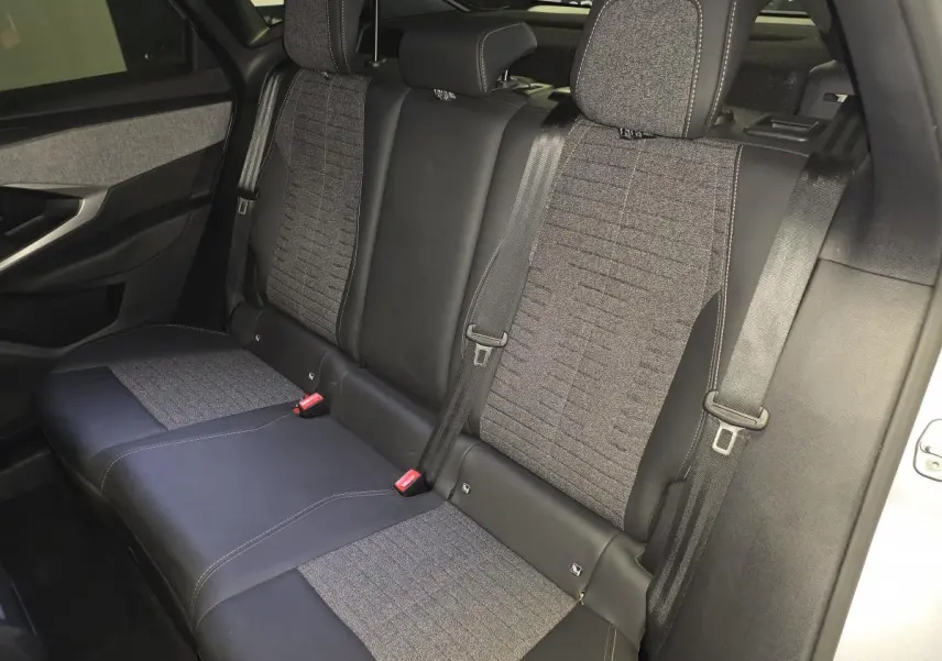 Vue intérieure de la banquette arrière du Peugeot 3008 hybride 2025, sellerie tissu gris et cuir noir.