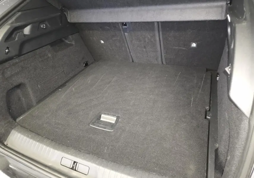 Vue intérieure du coffre spacieux et tapissé en tissu gris foncé du Peugeot 3008 hybride 2025.