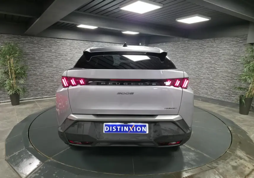 Vue arrière d'un Peugeot 3008 gris métallisé 2025 avec feux LED en forme de griffes et bandeau noir laqué entre les feux.