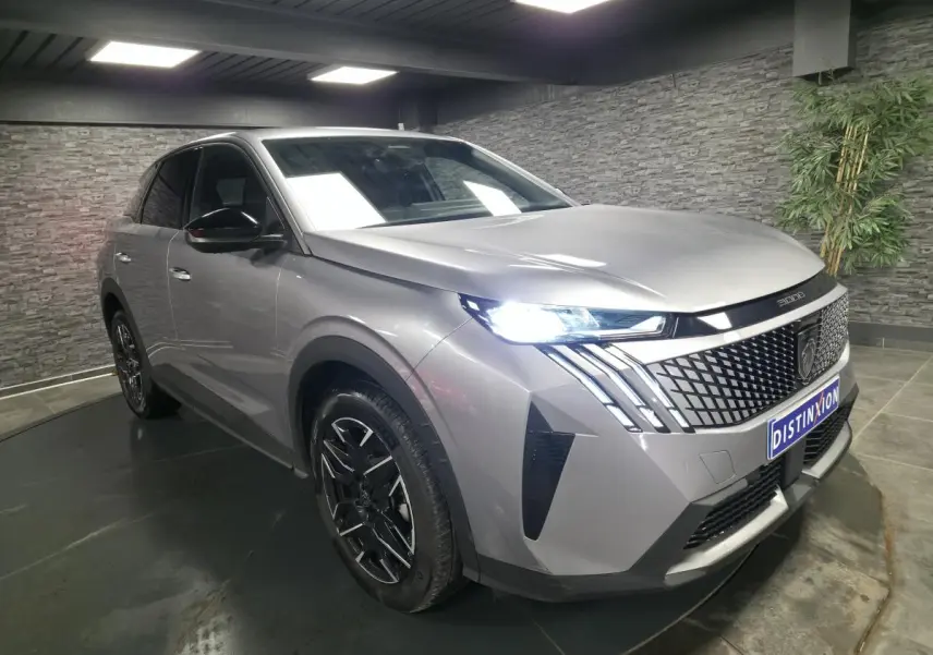 Peugeot 3008 gris métallisé vue 3/4 avant droit, avec calandre noire laquée et phares LED allumés.