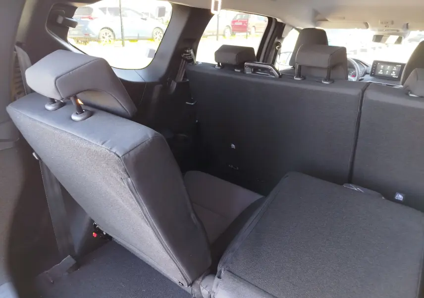 Vue intérieure arrière du Dacia Jogger 2026 montrant les sièges arrière en tissu noir, dont un partiellement rabattu.