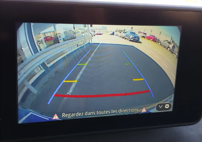 Vue de la caméra de recul du Dacia Jogger 2026, affichant les lignes de guidage sur un parking extérieur.