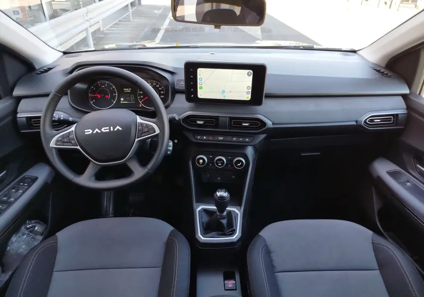 Vue intérieure avant du tableau de bord et volant noir de la Dacia Jogger 2026 avec écran tactile et boîte manuelle.