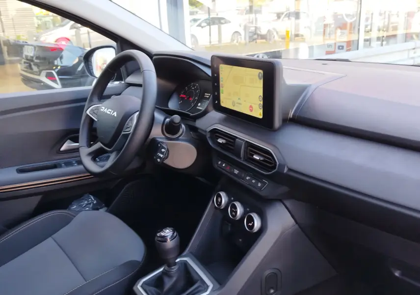 Intérieur avant droit du Dacia Jogger 2026, tableau de bord noir avec écran tactile et boîte manuelle visible.