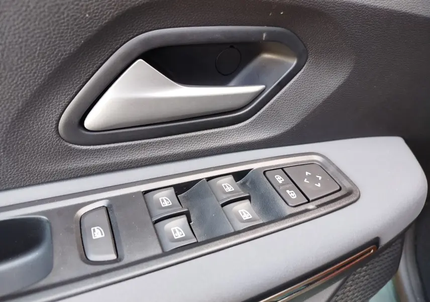 Gros plan sur la poignée intérieure et les commandes de lève-vitres côté conducteur du Dacia Jogger 2026, finition noire.