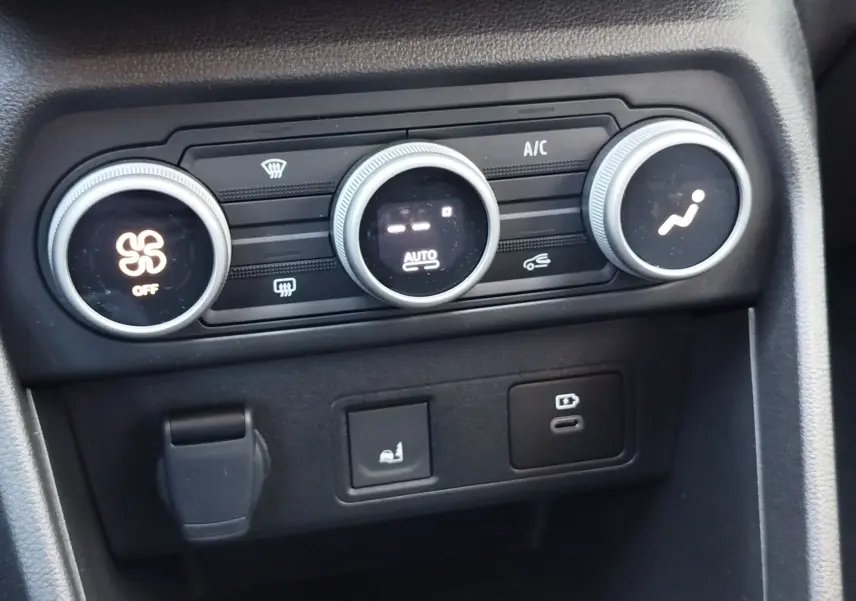 Vue rapprochée des commandes de climatisation et des prises USB dans le tableau de bord noir du Dacia Jogger 2026.