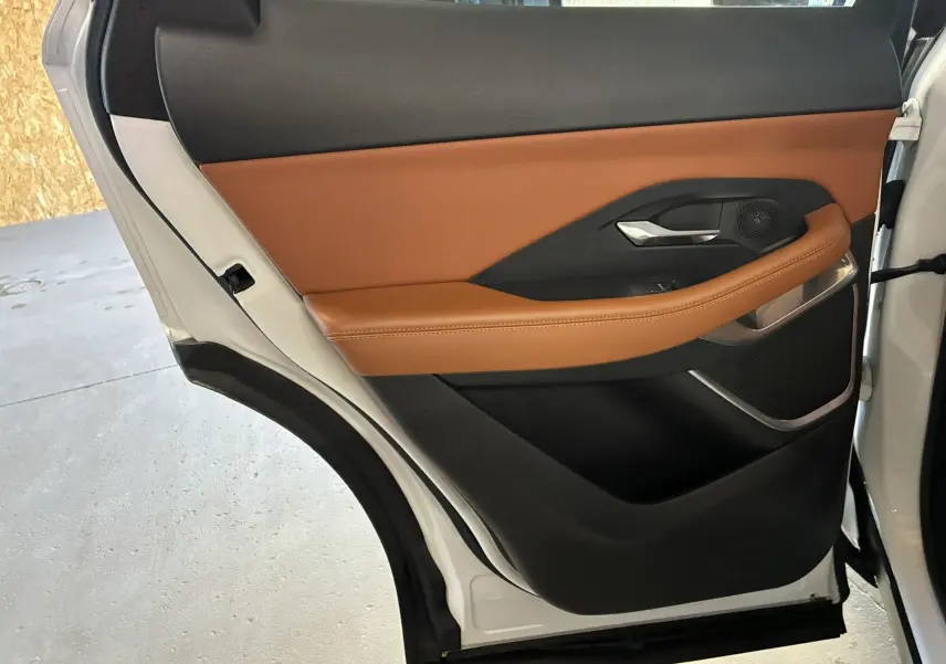 Vue intérieure de la porte arrière droite blanche du Jaguar E-PACE 2019 avec garniture cuir brun et détails noirs.