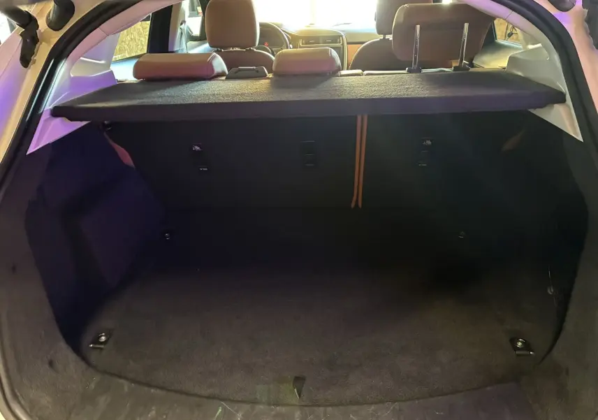 Coffre ouvert vu de l'arrière d'un Jaguar E-PACE blanc, montrant l'espace de chargement et la tablette cache-bagages.