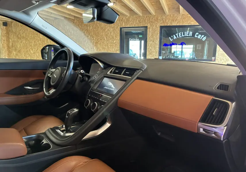 Vue intérieure côté conducteur du Jaguar E-PACE 2.0D 180 R-DYNAMIC HSE avec sellerie cuir brun et tableau de bord noir et marron.