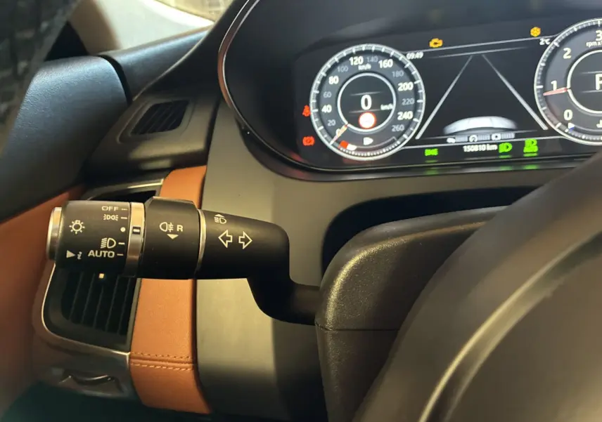 Vue intérieure rapprochée du commodo d’éclairage et du tableau de bord digital d’un Jaguar E-PACE 2019 avec sellerie cuir brun.